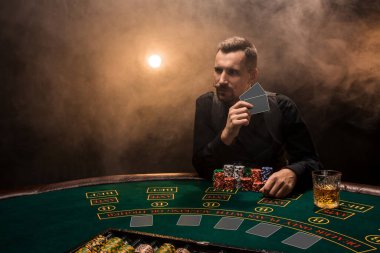 Adam puro ve viskiyle poker oynuyor. Masadaki tüm cipsleri sigara dumanıyla kazanan bir adam. Zafer konsepti