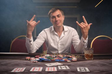 Yakışıklı duygusal adam kumarhanede masada poker oynuyor..