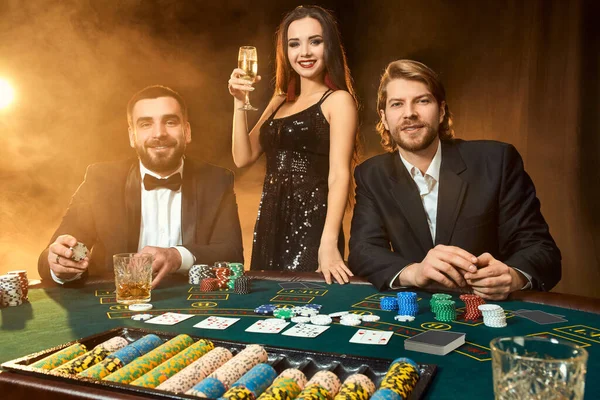 一群富有的年轻人在赌场里打扑克 两个穿西装的男人和一个穿黑衣服的年轻女人 卡西诺扑克 — 图库照片