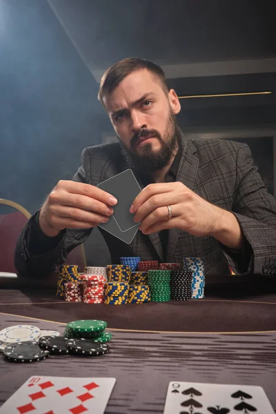 Vousáč Šedém Obleku Hraje Poker Sedí Stolu Kasinu Kouří Rukou — Stock fotografie