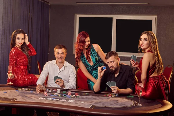 Bir grup heyecanlı genç arkadaş kumarhanede poker masasında oynuyorlar ve kameraya bakıyorlar. Gençler büyük bir galibiyet için bahis oynuyorlar. Para için kumar oynuyorum. Şans oyunları..