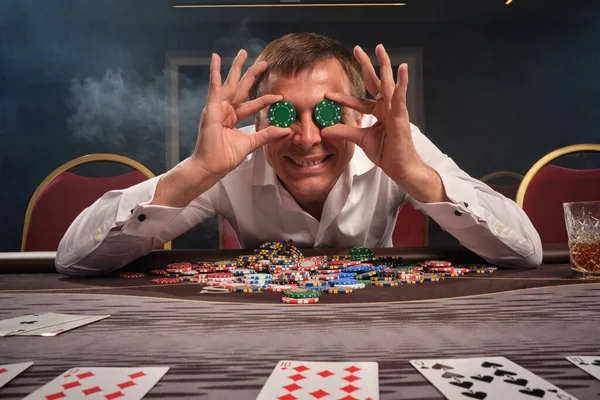 Schöner emotionaler Mann pokert am Tisch im Casino. — Stockfoto