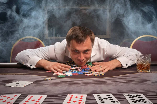 Snygg känslomässig man spelar poker sitter vid bordet i kasino. — Stockfoto