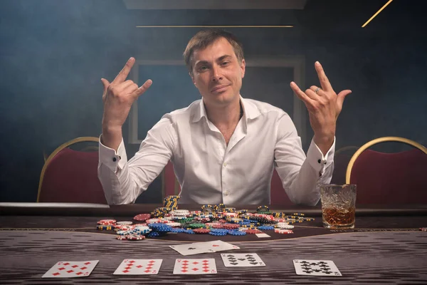 Przystojny emocjonalny mężczyzna gra w pokera siedząc przy stole w kasynie. — Zdjęcie stockowe