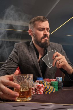 Yakışıklı sakallı adam kumarhanede masada poker oynuyor..