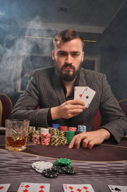Yakışıklı sakallı adam kumarhanede masada poker oynuyor..