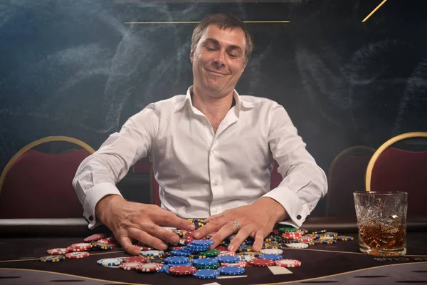 Hombre guapo emocional está jugando póquer sentado en la mesa en el casino . — Foto de Stock