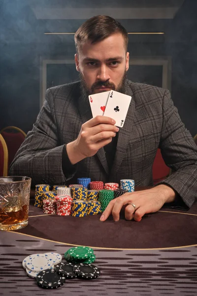 Красивий бородатий чоловік грає в покер, сидячи за столом в казино . — стокове фото