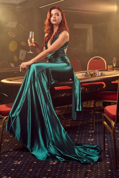 Fiatal gyönyörű nő pózol egy pókerasztal ellen a luxus kaszinóban.. — Stock Fotó