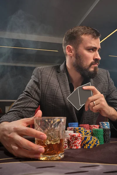 Красивый бородатый мужчина играет в покер, сидя за столом в казино . — стоковое фото
