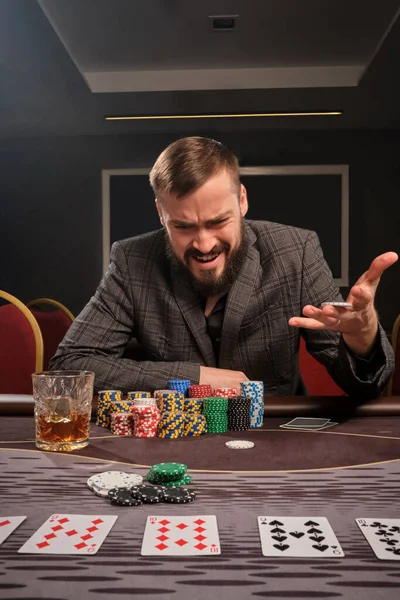 Hombre barbudo guapo está jugando póquer sentado en la mesa en el casino . —  Fotos de Stock