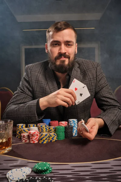 Hezký vousatý muž hraje poker sedí u stolu v kasinu. — Stock fotografie