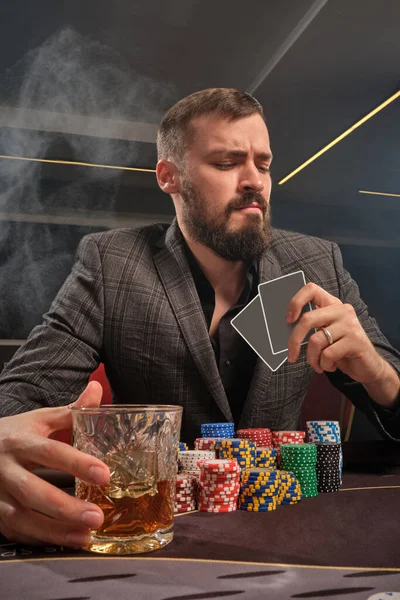 Snygg skäggig man spelar poker sitter vid bordet i kasino. — Stockfoto