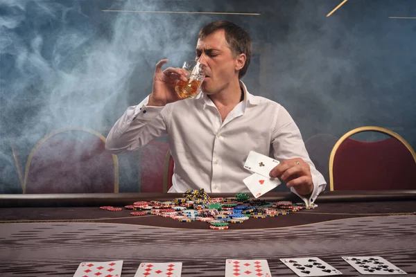 Bel homme émotionnel joue au poker assis à la table dans le casino . — Photo