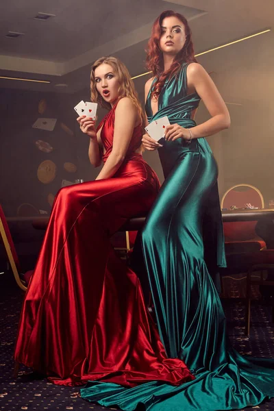 Due belle donne stanno posando contro un tavolo da poker nel casinò di lusso . — Foto Stock