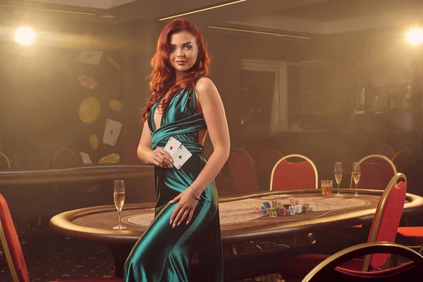 Mladá krásná žena pózuje proti pokerovému stolu v luxusním kasinu. — Stock fotografie