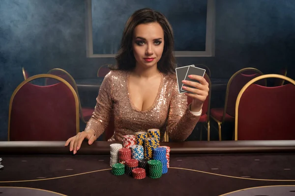 Красивая брюнетка играет в покер сидя за столом в казино . — стоковое фото