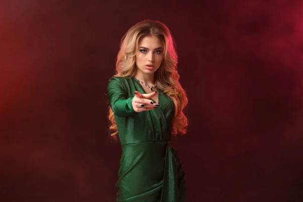 Blond kvinna, smink, i grön stilren klänning och smycken. Le, hålla något på handflatan, posera på färgglada rökig bakgrund. Närbild — Stockfoto