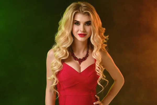 Chica rubia con maquillaje brillante, en vestido rojo apropiado y collar. Sonriendo, posando sobre un colorido fondo de estudio ahumado. Moda y belleza. De cerca. — Foto de Stock