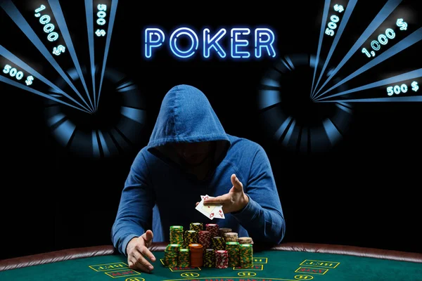 Mannen i blå luvtröja visar ess, sitter vid spelbordet med högar av marker. Svart bakgrund med neon dollar belopp, inskription poker. Kasino — Stockfoto