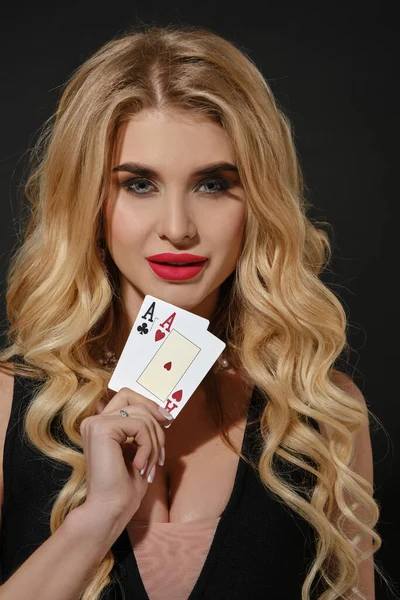 ゴージャスな巻きブロンドの女の子 明るいメイクアップ 黒のスタイリッシュなドレスやネックレス 彼女は笑顔で 2枚のトランプを見せ 黒い背景にポーズをとっている ポーカー カジノ コピースペース — ストック写真