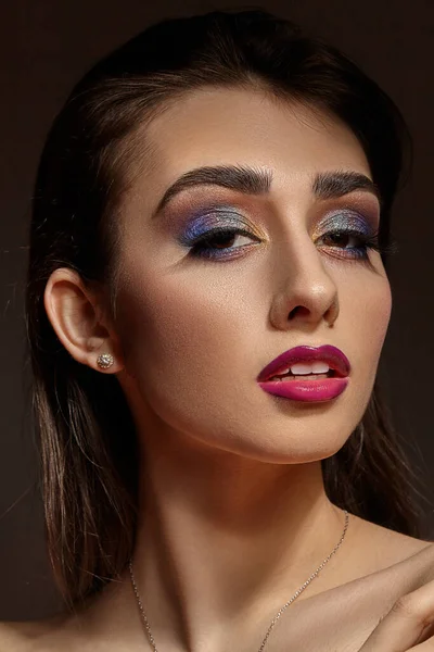 Naakt model in ketting en oorbellen poseren op grijze achtergrond. Heldere make-up, perfecte huid. Kleurrijke oogschaduw, lange wimpers, rode lippen. Sluiten. — Stockfoto