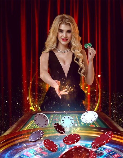 Kobieta w czarnej sukience uśmiecha się, trzymając dwa zielone żetony i rzucając kolorowe na ruletkę. Pozowanie przeciwko czerwonym zasłonom. Poker, kasyno. Zamknij się. — Zdjęcie stockowe