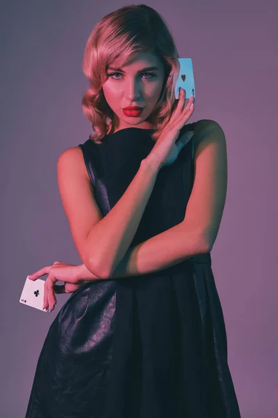 Blonde girl in black stylish dress showing two playing cards, posing  against colorful background. Gambling entertainment, poker, casino.  Close-up. — blackjack, player - Stock Photo | #322073420