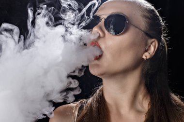 Kız bir siyah arka plan vape yükselir