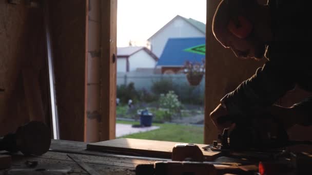 Jonge vet timmerman met snor. cirkelzaag snijden stuk hout. zon flare op achtergrond — Stockvideo