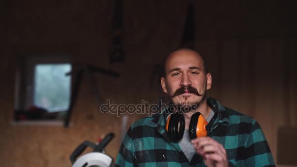 Retrato de um carpinteiro trabalhador ousado com bigode vintage em roupas de trabalho na frente de ferramentas de bancada — Vídeo de Stock