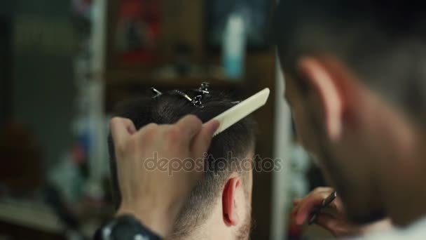 Jovem barbeiro aparar homens cabelo com tesoura na barbearia — Vídeo de Stock