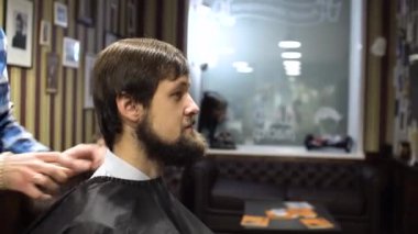 Uzun saç Kuaför berber dükkanı genç sakallı adam için bir saç kesimi yapıyor. 4k