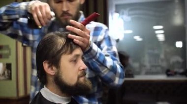 Uzun saç Kuaför berber dükkanı genç sakallı adam için bir saç kesimi yapıyor. 4k