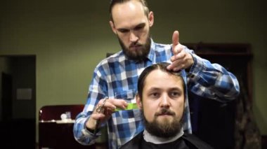 Çekici genç Kuaför insan saçı makasla kesme. Konsantrasyon ile saçlara arıyor. Sakallı adam çenesini yetiştirme