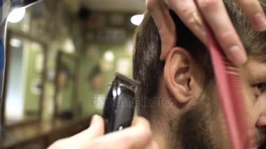 Onun müşteri ile tarak ve düzeltici dikkatle bir saç kesimi veren sakallı bir Kuaför portresi. 4k