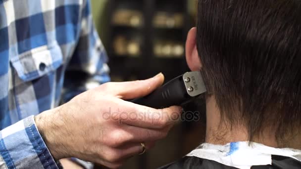 Potret seorang tukang cukur berjanggut memberikan potongan rambut kepada kliennya dengan sisir dan pemangkas penuh perhatian. 4K — Stok Video