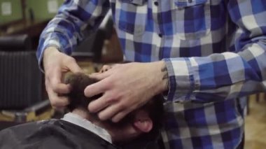 Kuaför sakalı sakallı bir adam bir kuaför dükkanında saç kurutma makinesi ile kurutma