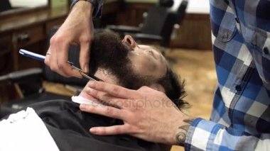 Adam olan kuaför dükkanında tıraş yakın çekim. Profesyonel kuaför Usturanın keskin bıçak ve krem jel ile müşteri yüzüne bıyık, saç kılları kesmek için kullanma. Mutlu gülümseyen memnun Berber Dükkanı