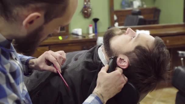 Kapper vrouw trimmen baard voor client met clipper op barbershop — Stockvideo