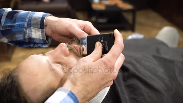 Hårstyling process. Närbild av en barberare torkning håret av skäggiga ung — Stockvideo