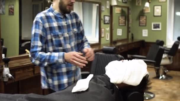 Homme préparé pour un rasage traditionnel avec un rasoir dans un salon de coiffure. 4K — Video