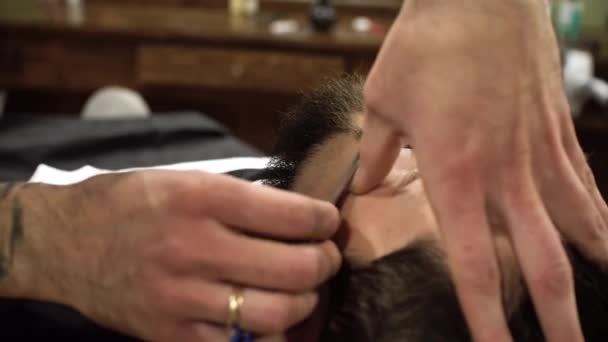 Geconcentreerde Kapper scheren baard voor client met barber scheermes — Stockvideo