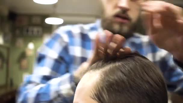 Hairstyling process. Close-up of a barber drying hair of a young bearded man — Stock Video