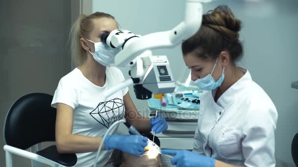 Médico dentista com o assistente no trabalho da clínica com monitor de referência — Vídeo de Stock