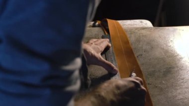 20'li yaşlarda genç adam atölyesinde DIY araçları işçiliği kullanarak deri ile çalışma