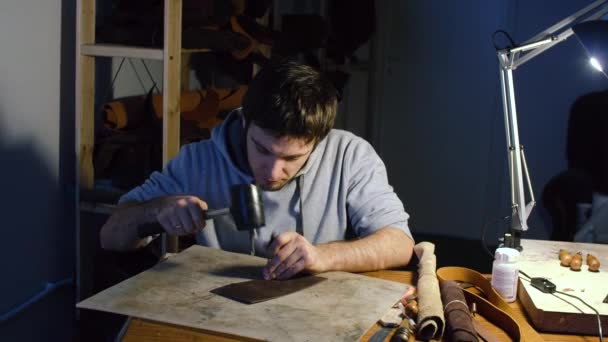 Человек работает на коже, делает отверстия с помощью Hummer — стоковое видео