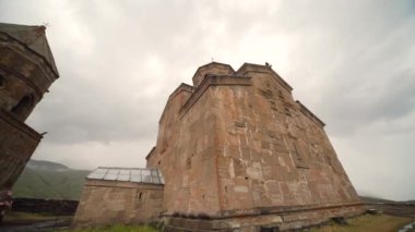 Dağlarda eski kilise önünde duran genç kadın turist
