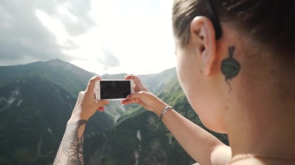 Primo piano mano della donna che tiene smartphone scattare foto in vista delle montagne . — Video Stock