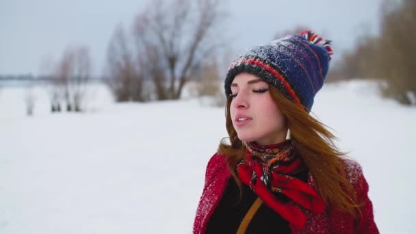 Портрет молодой рыжей женщины, вдыхающей холодный воздух на снежном поле — стоковое видео